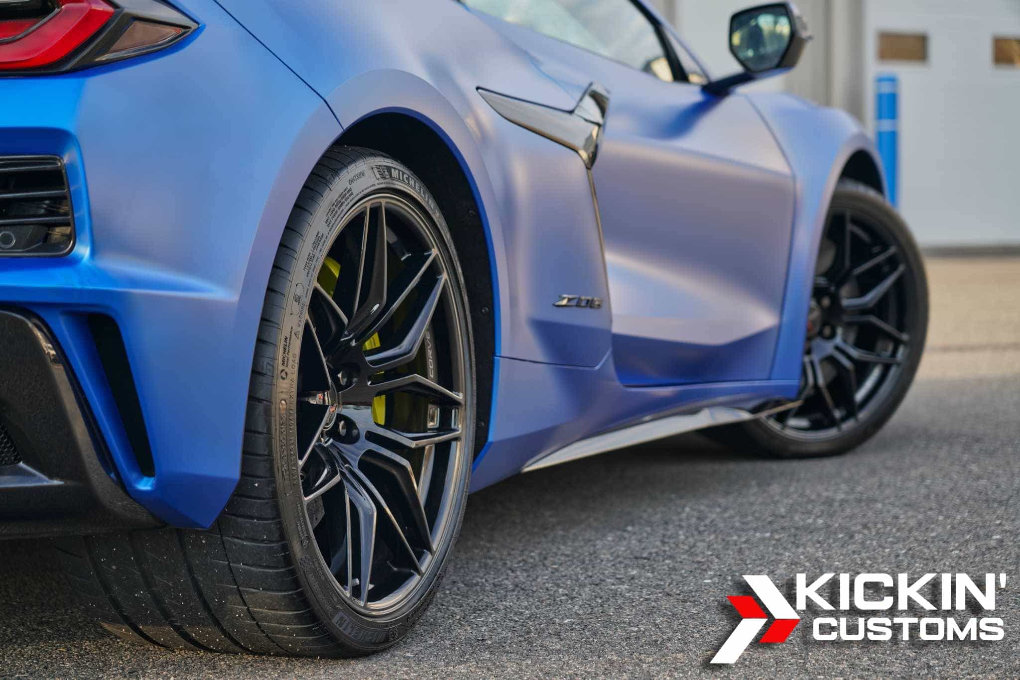 Close-up of a matte blue Corvette Z06 protected with XPEL Stealth Paint Protection Film, parked outside a shop in Boxborough, MA. The self-healing film preserves the satin finish while enhancing gloss and shielding against chips and scratches.